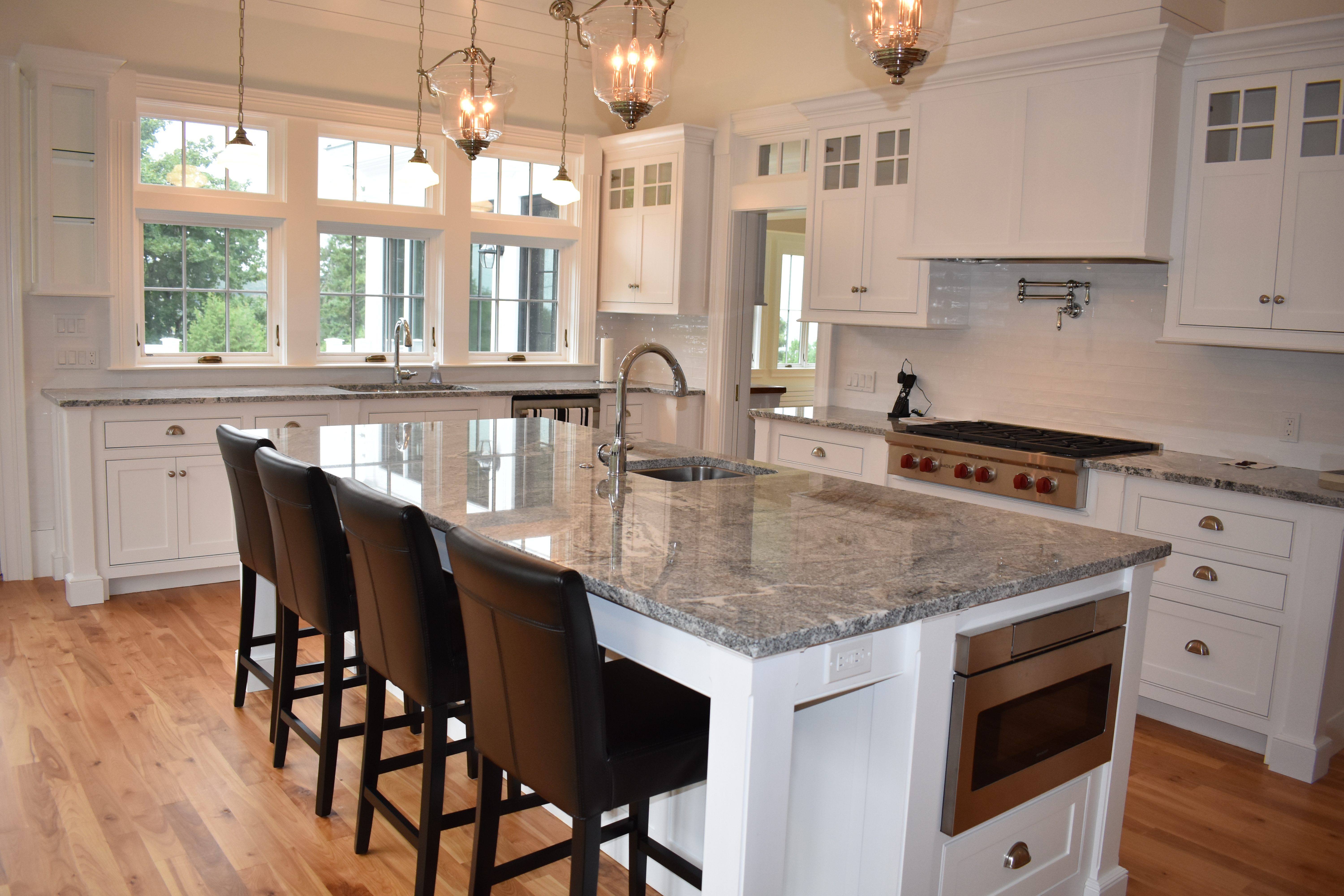 Custom white kitchen with island seating and range wall