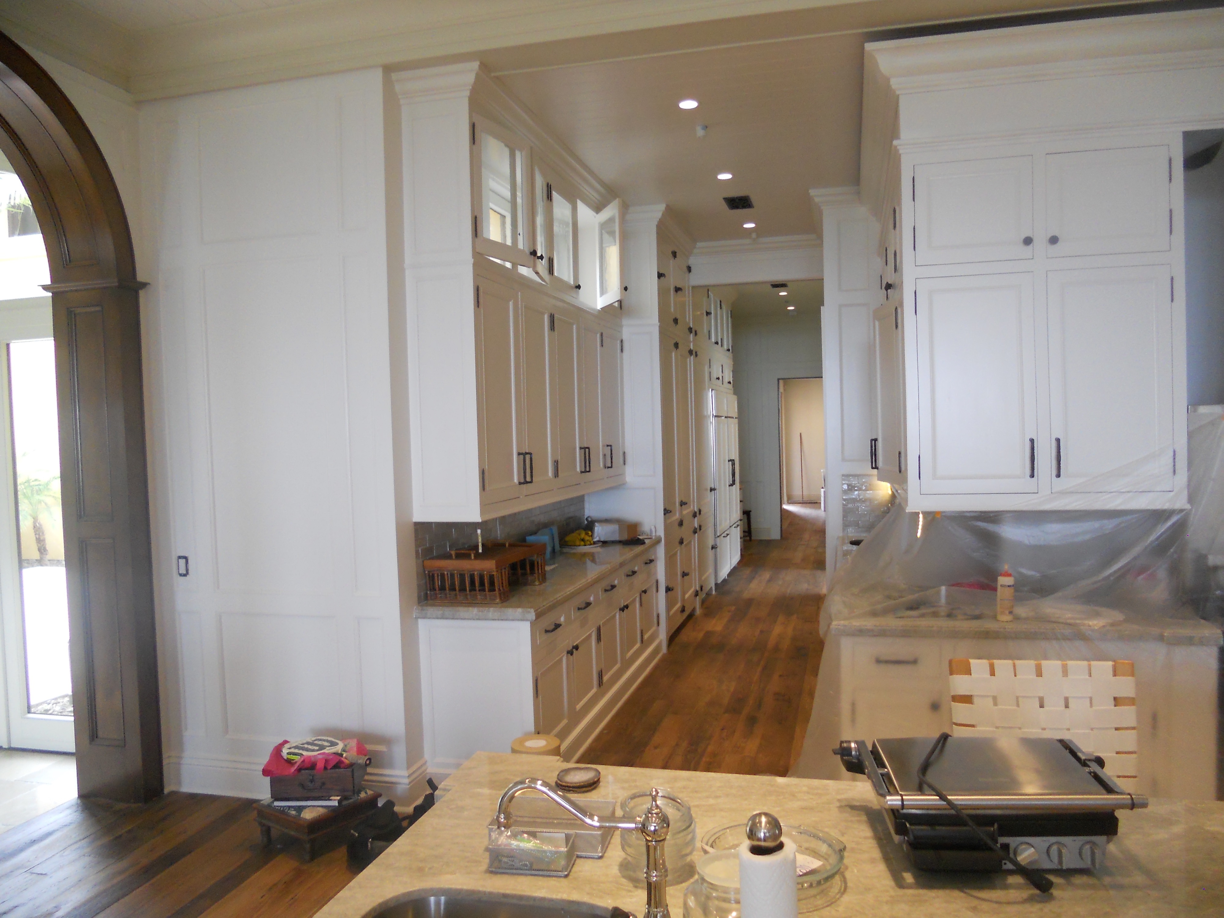 White kitchen cabinetry with arched opening and long counter