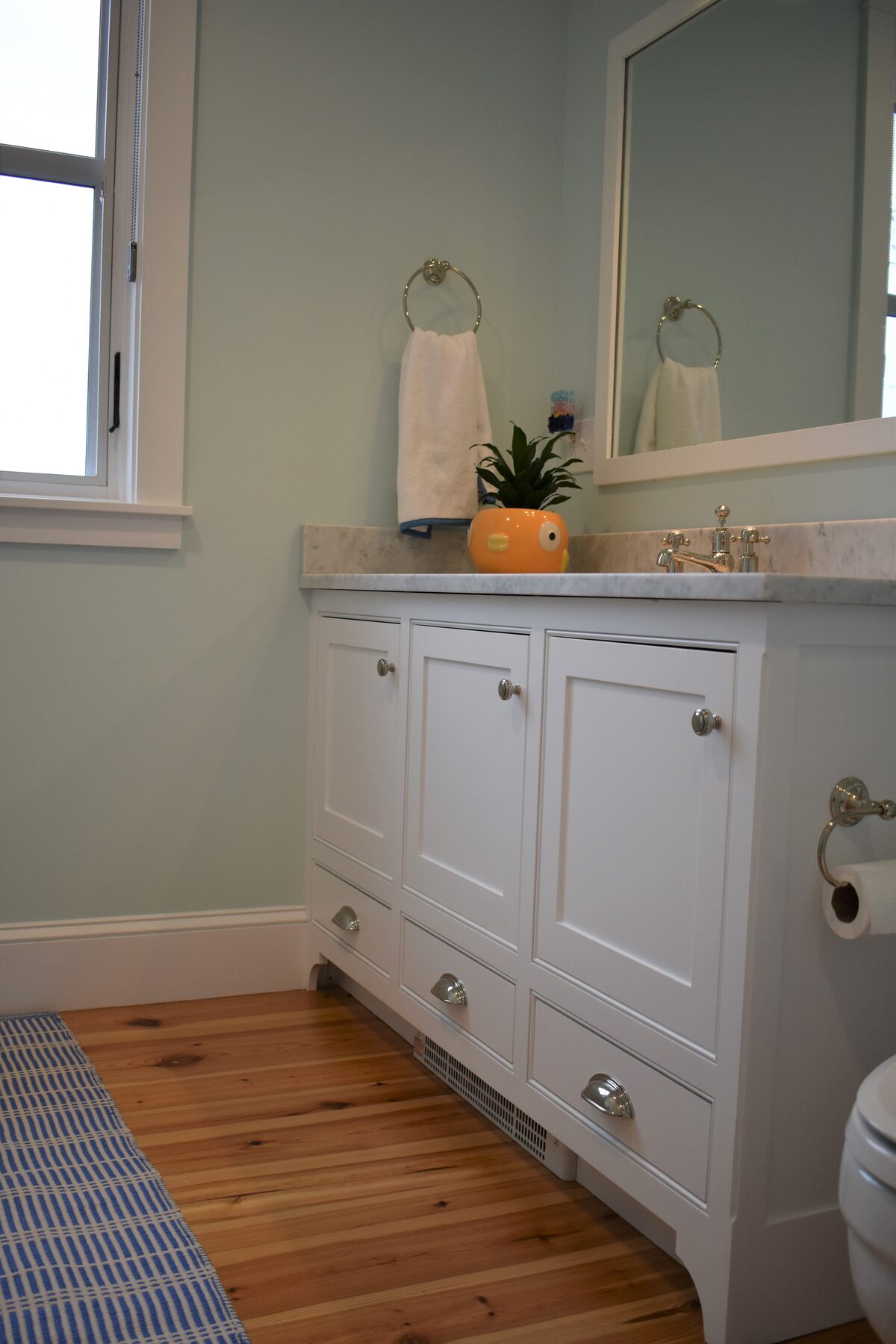White powder room vanity and wood flooring