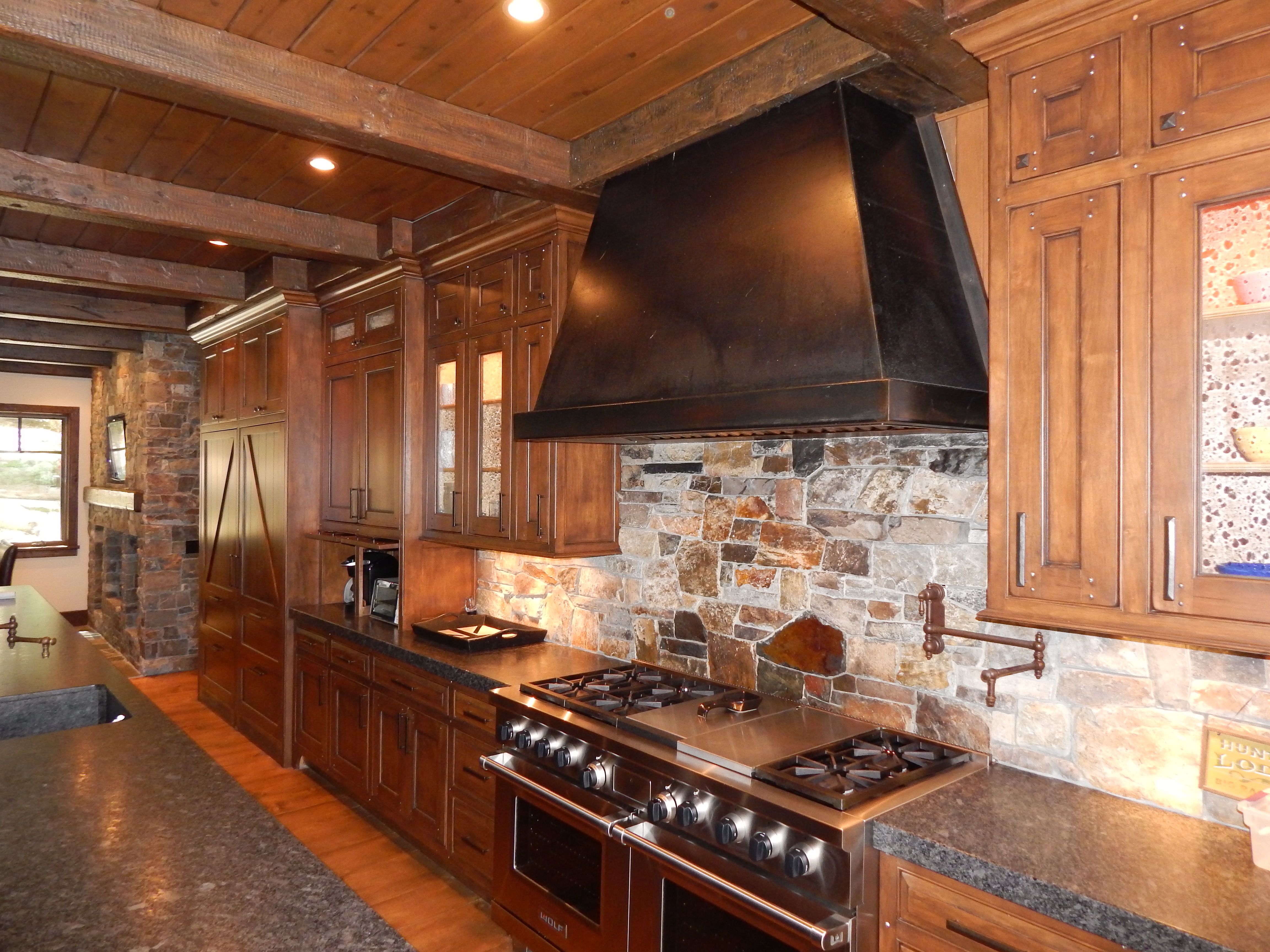 Wood kitchen range wall with custom hood and stone backsplash