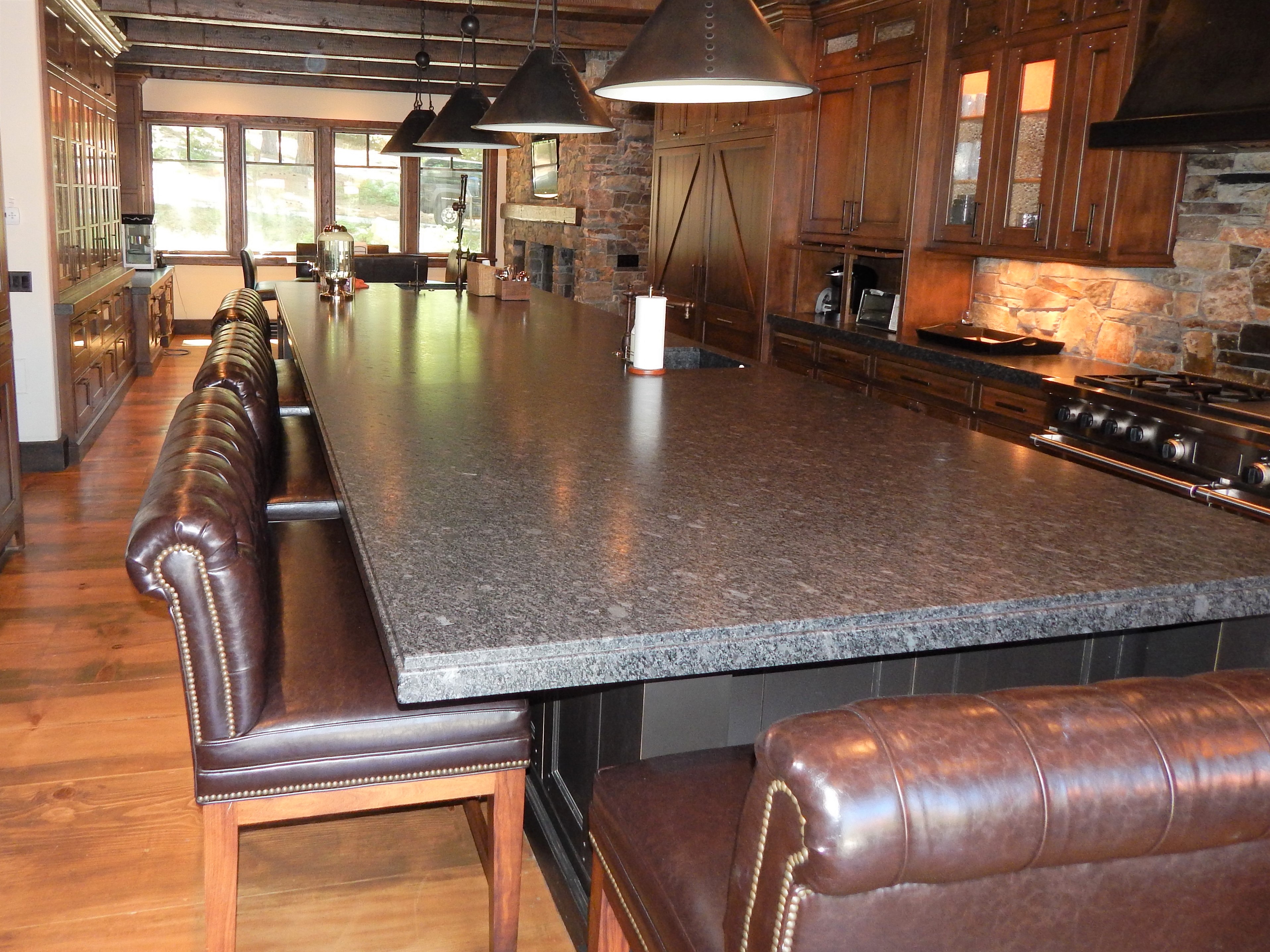Dark kitchen island with stone countertop and leather seating