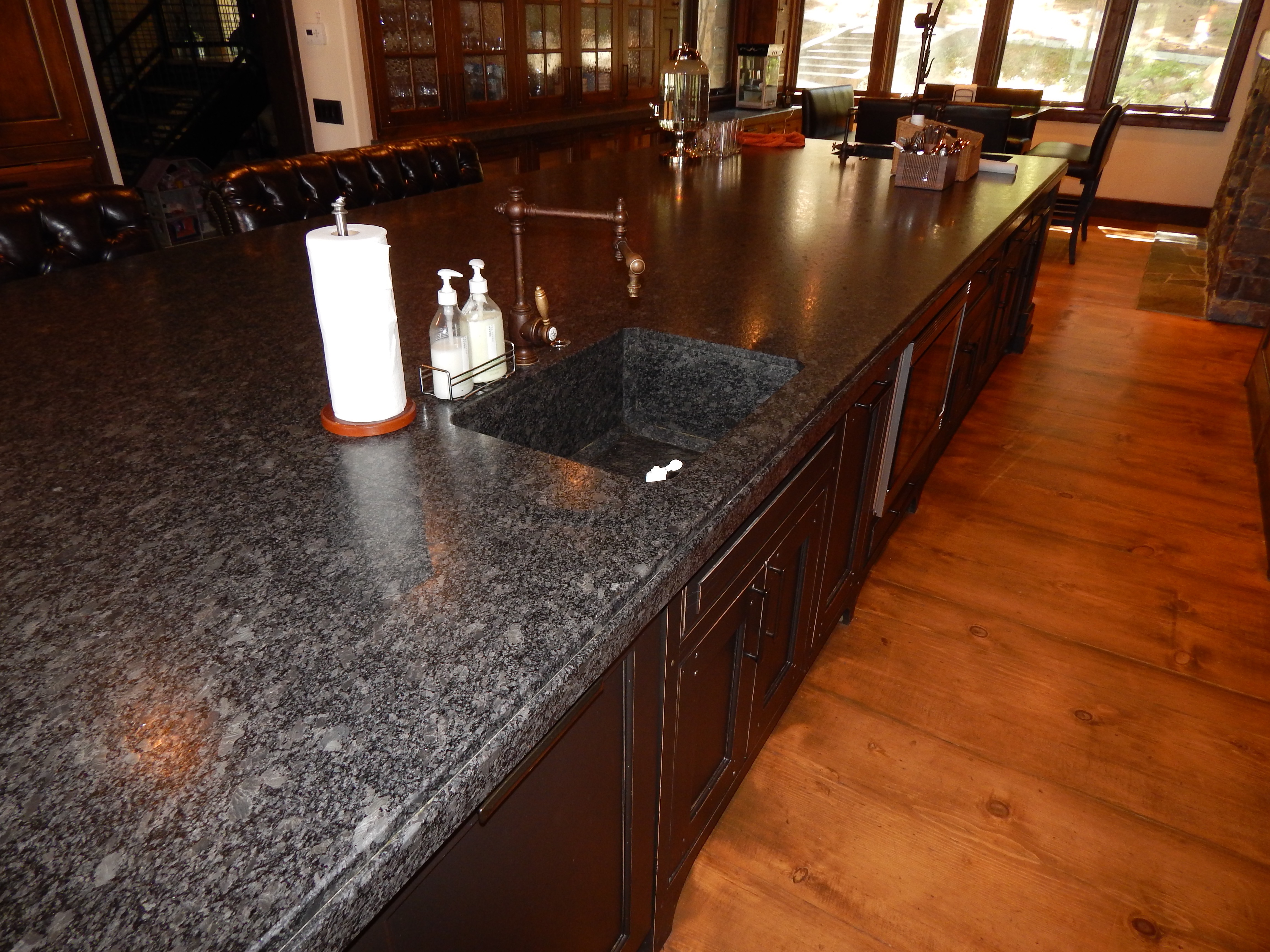 Dark stone island countertop with sink and wood cabinetry