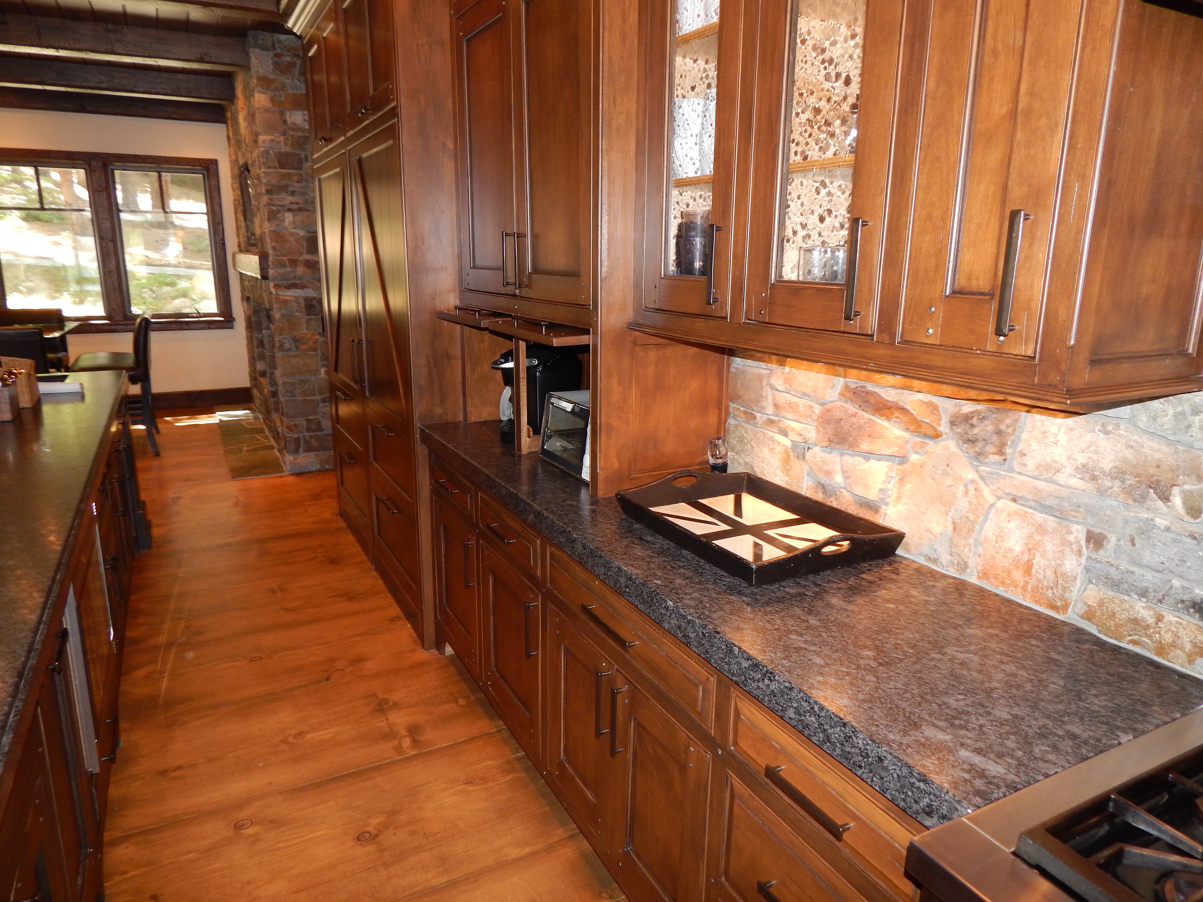 Wood kitchen counter with stone backsplash and glass cabinet doors