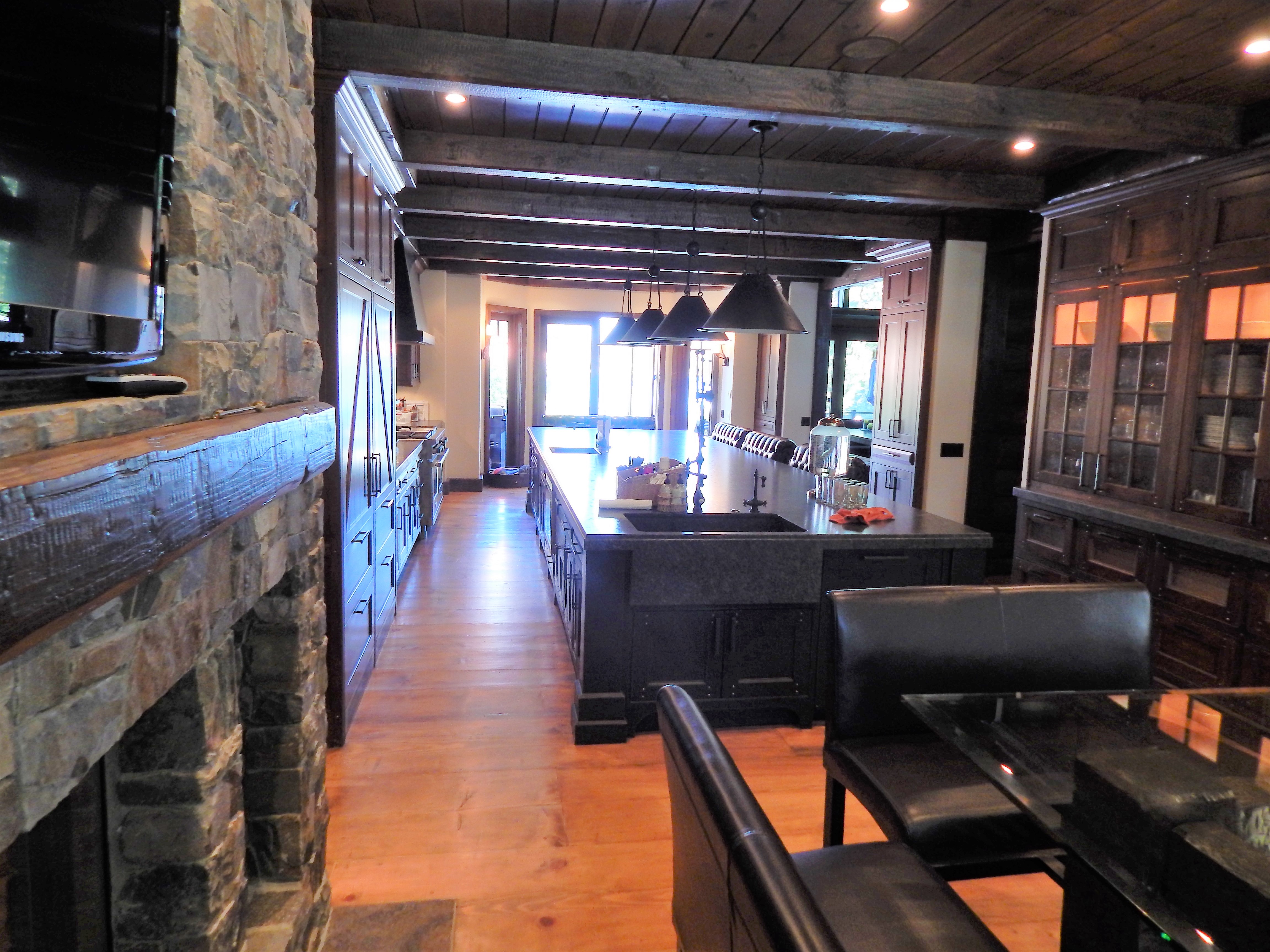 View from stone fireplace into rustic wood kitchen