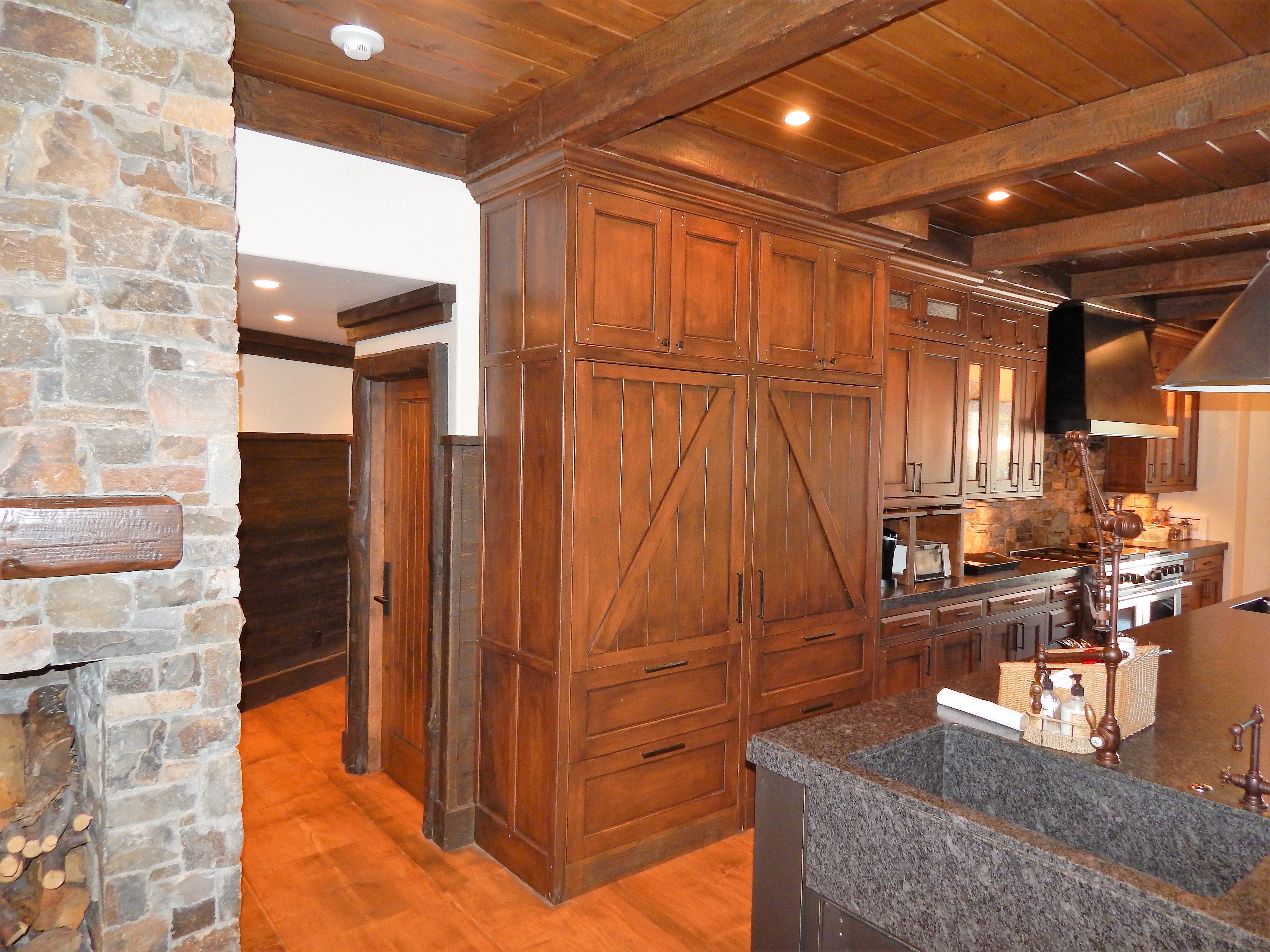 Rustic wood kitchen with dark island and paneled cabinetry